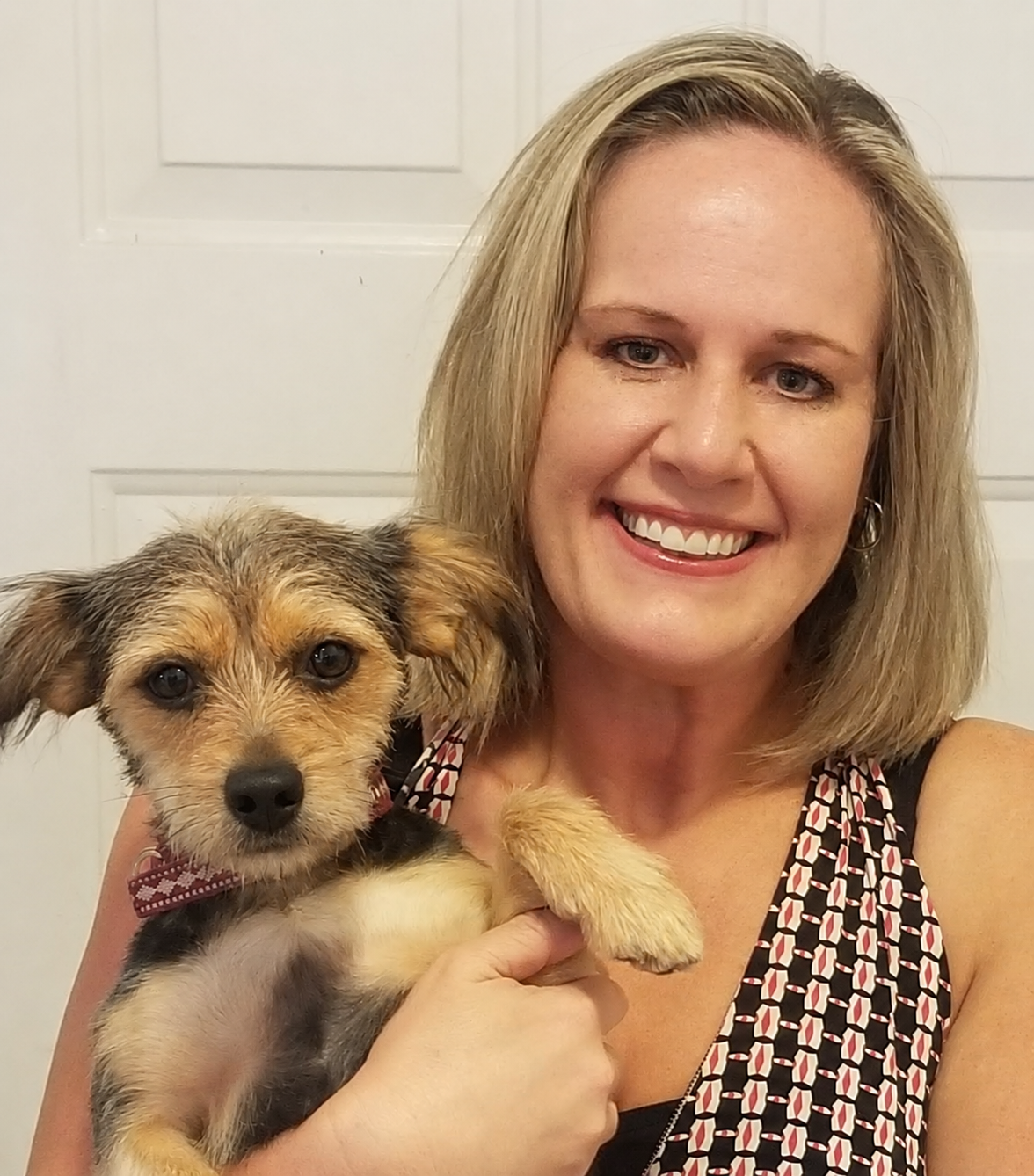 Stacie Long smiling while holding her happy dog